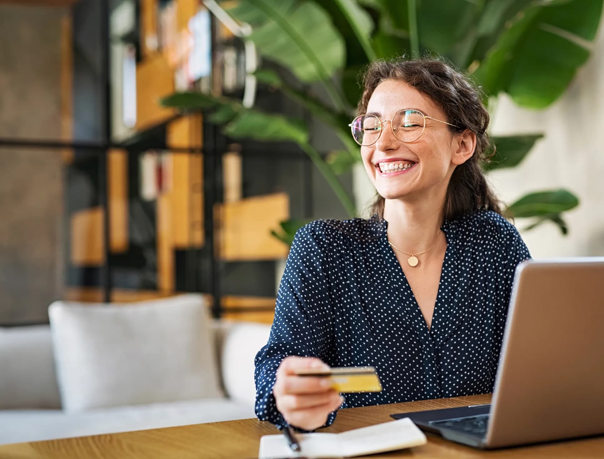 A smiling woman holding her card in front of a laptop
